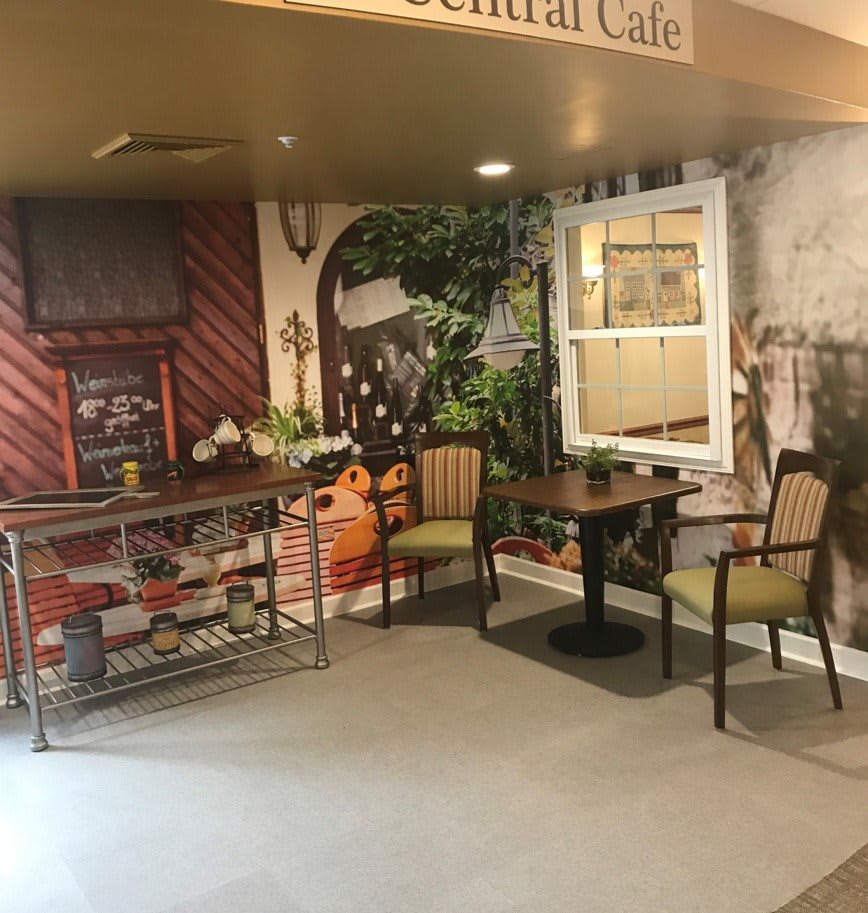 A cozy indoor cafe setting with a decorative wall mural and seating area.