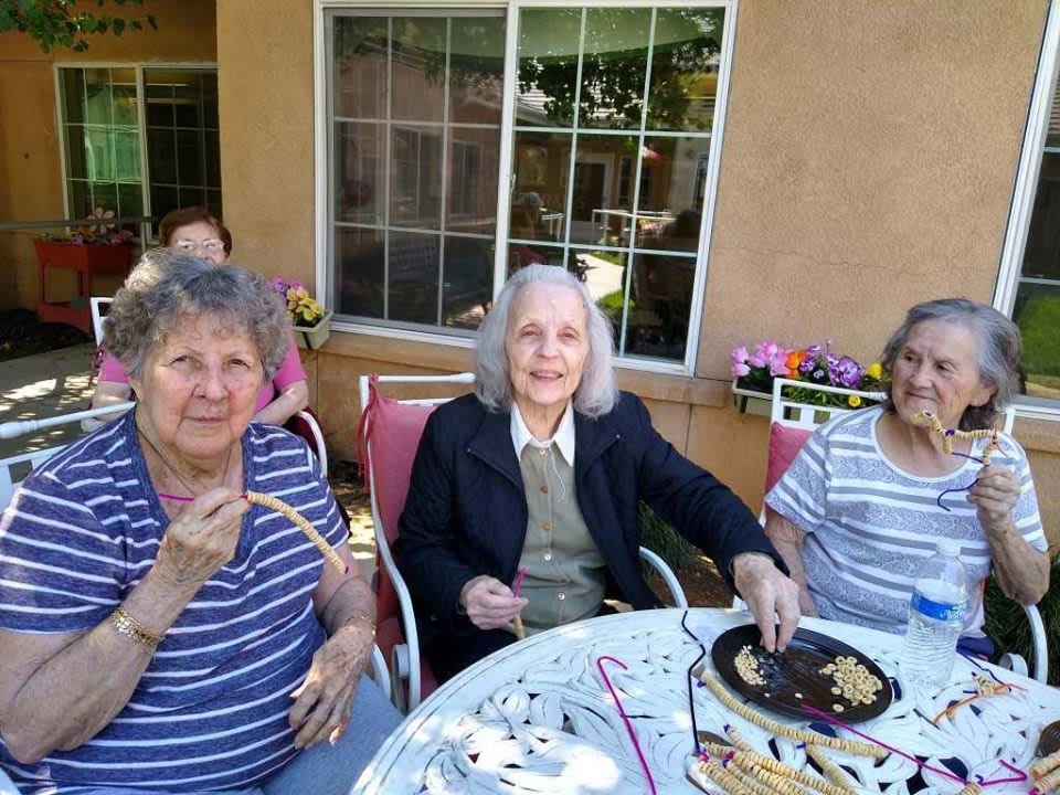 A group of elderly women enjoying a social gathering outdoors with snacks.