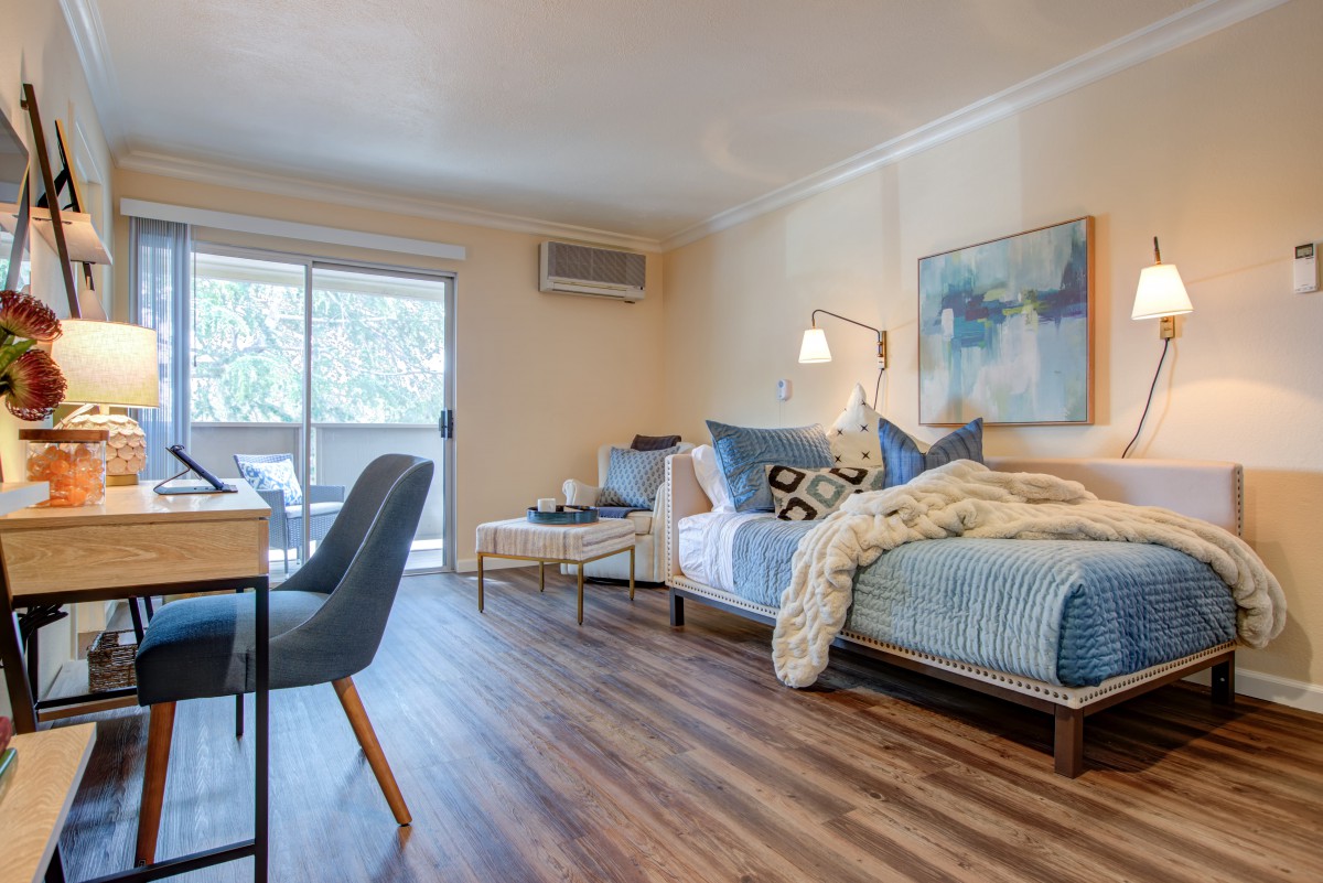 A modern open-plan apartment featuring a combined living and bedroom area with stylish furnishings and wood flooring.