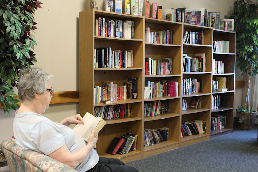 A person enjoying a book in a cozy library setting surrounded by books.