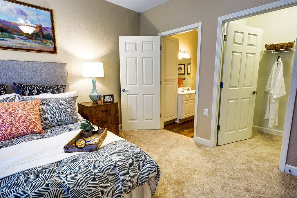 A cozy bedroom with a bed, nightstand, and open doors leading to adjoining rooms.