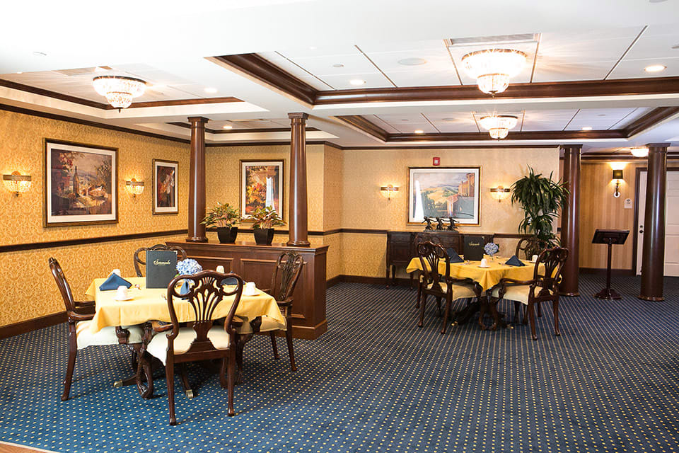A well-decorated dining room with multiple tables and chairs, adorned with artwork on the walls.