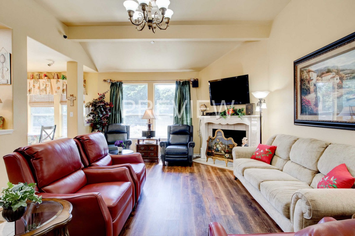 A spacious living room with comfortable seating, a fireplace, and a mounted television.