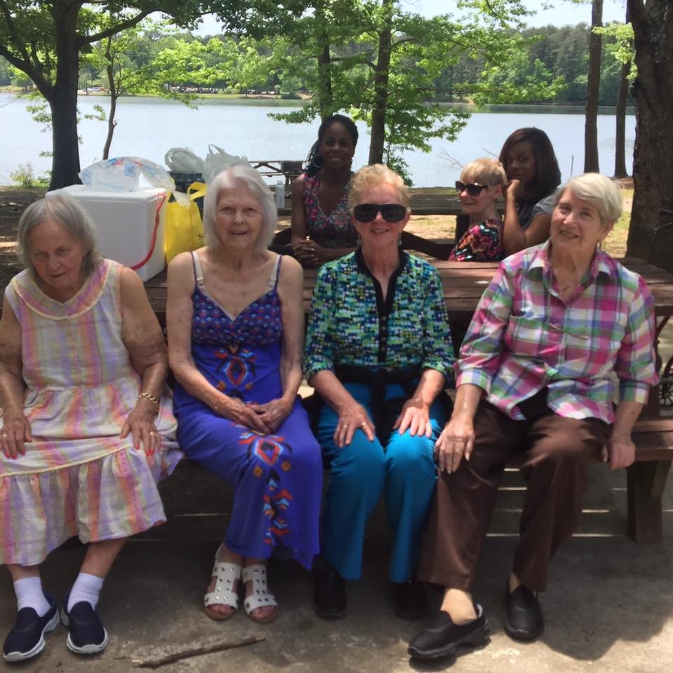 A group of elderly women sitting on a bench in a park.