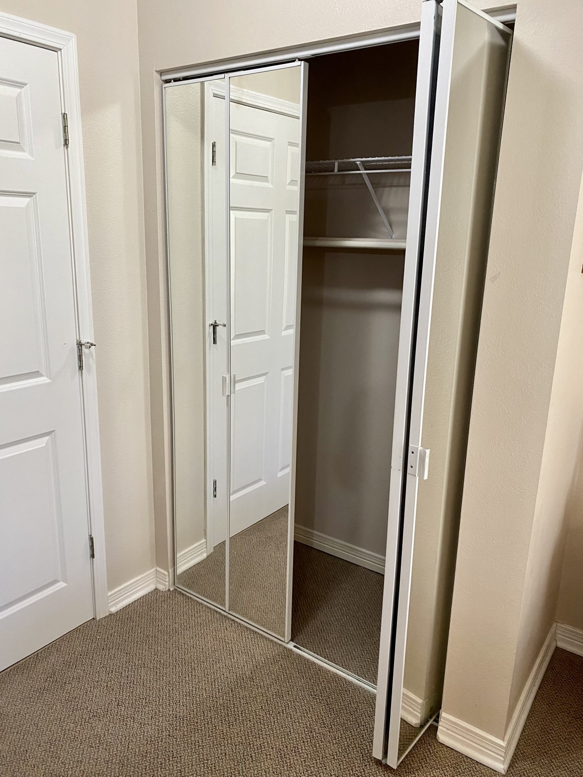 An empty closet with mirrored sliding doors and a shelf inside.