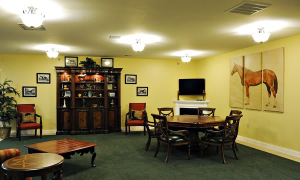 A cozy living room with a dining table, cabinet, and television, adorned with artwork.
