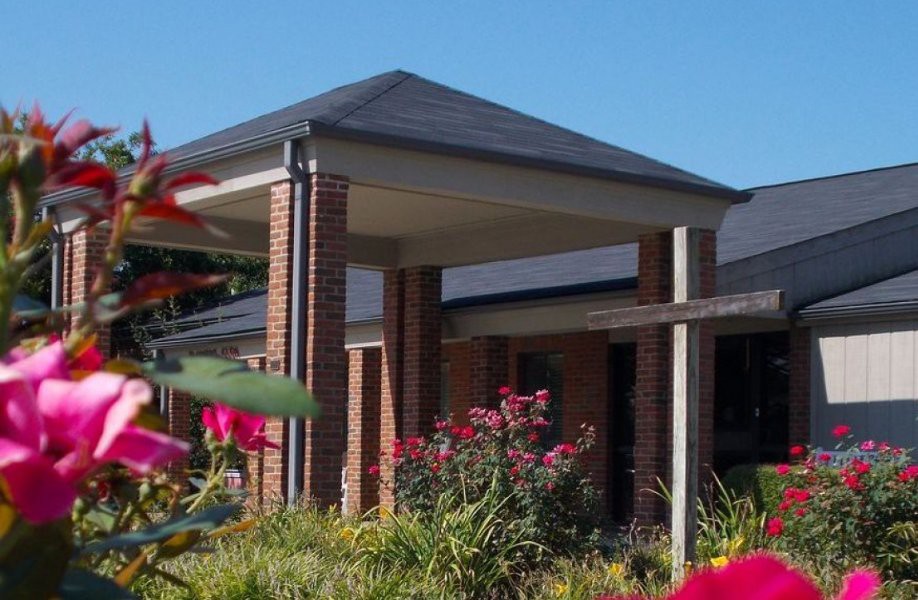 A brick building with a sloped roof surrounded by a garden with vibrant flowers.