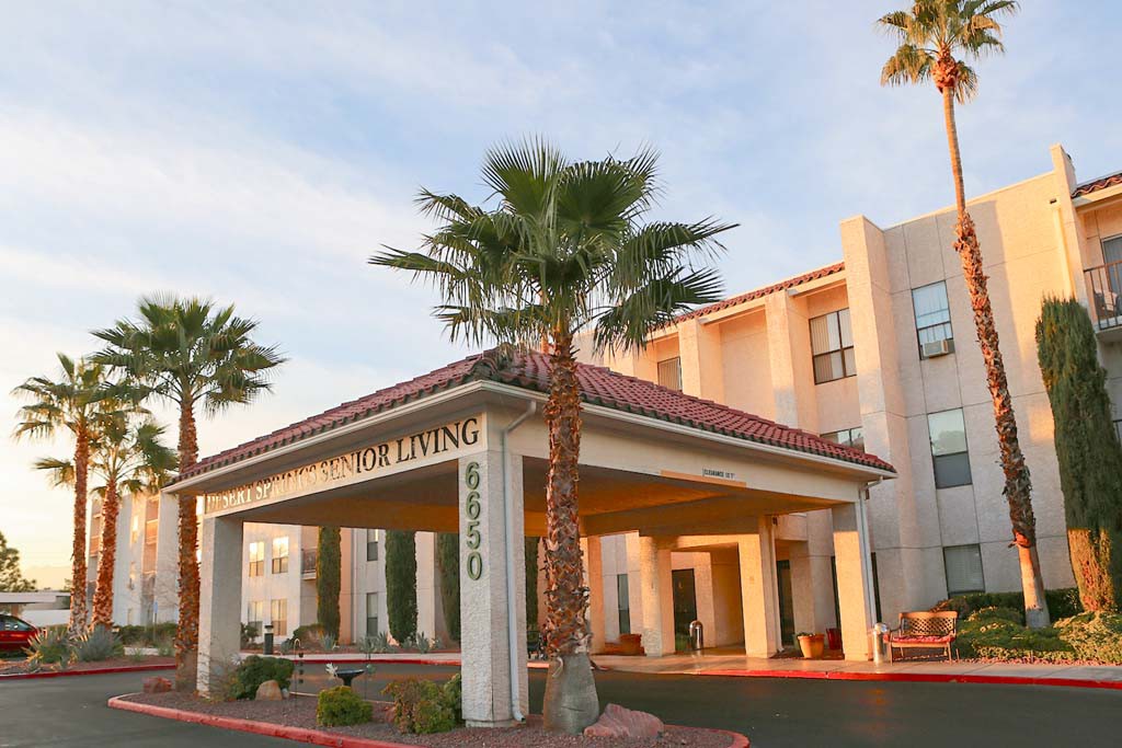 A hotel entrance surrounded by palm trees in a sunny setting.