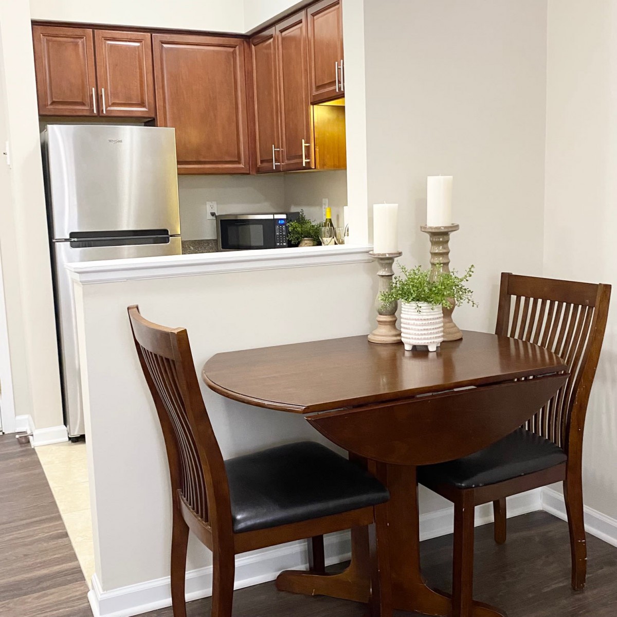 A cozy dining area with a wooden table and chairs, adjacent to a modern kitchen.
