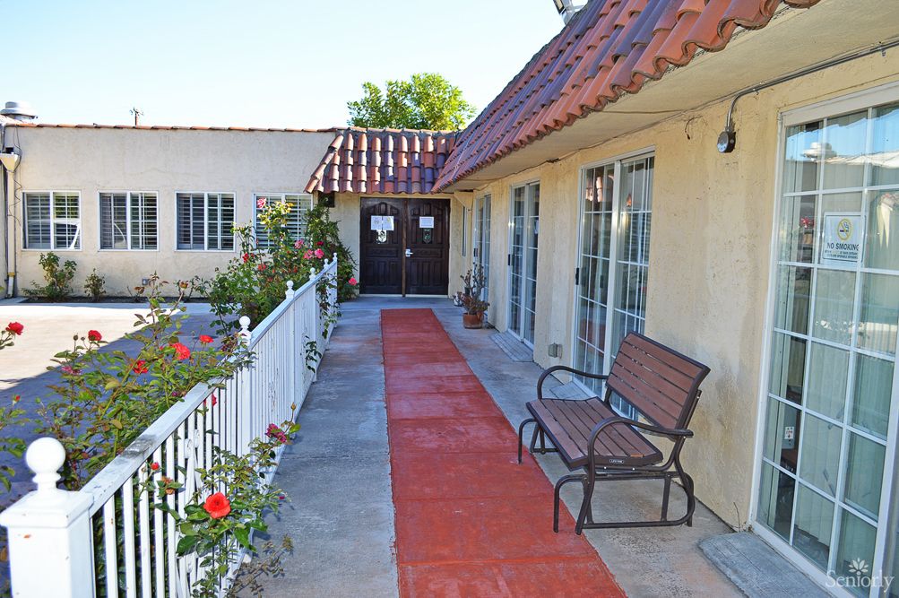 A quaint outdoor walkway with a bench and blooming flowers lining the path.