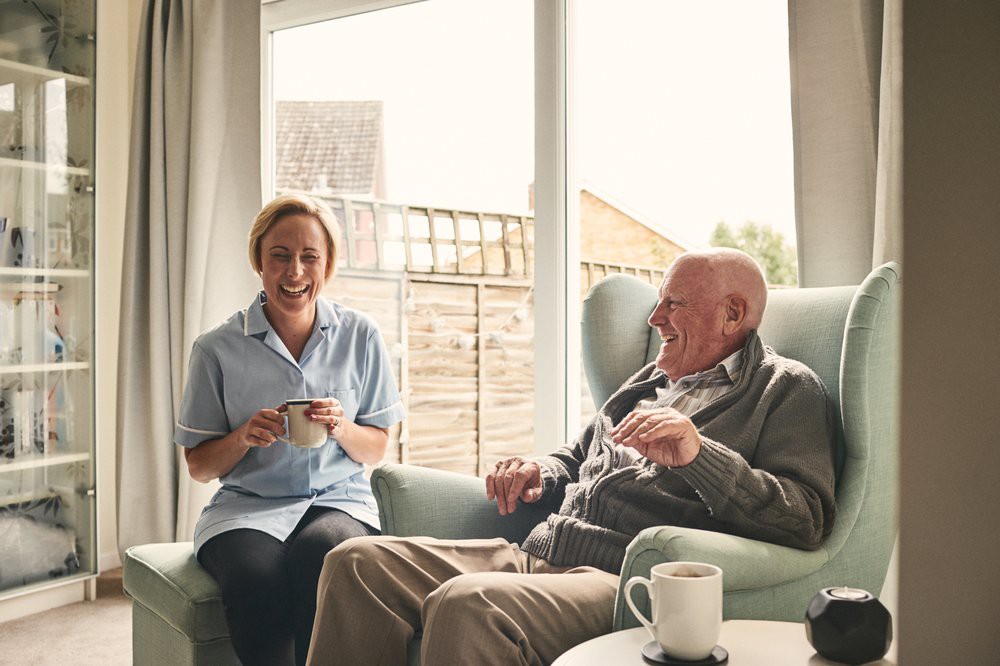 A nurse and an elderly man sharing a moment in a cozy living room.