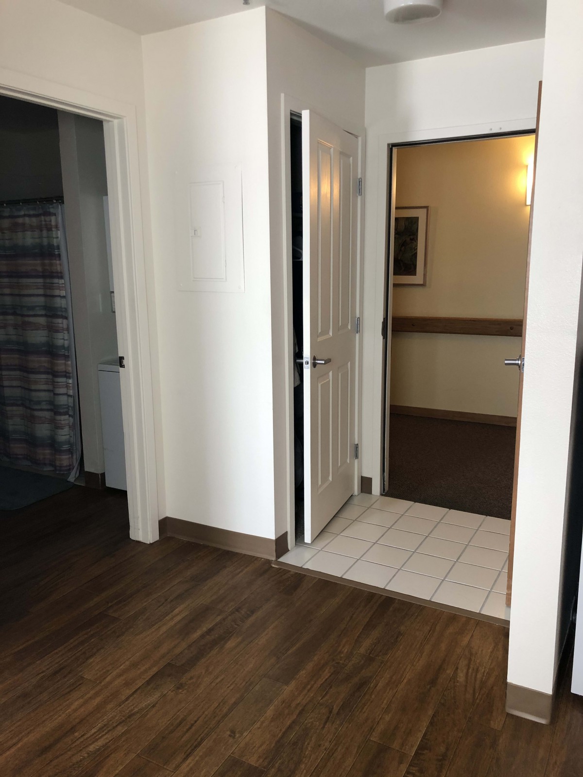A modern interior hallway with wooden and tiled floors, featuring multiple doors.