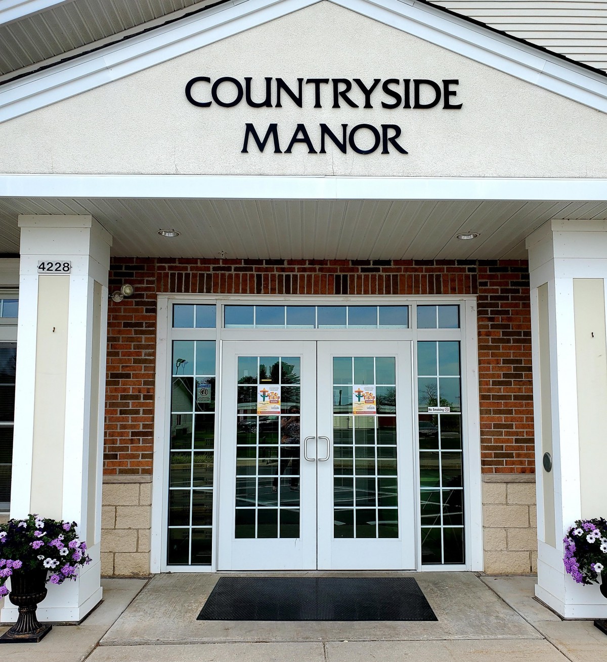The entrance to Countryside Manor with large glass doors and a sign above.