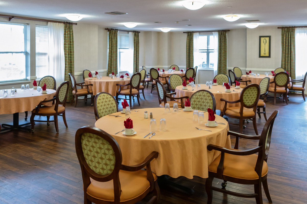 An elegant dining room with round tables and chairs, set for a meal.
