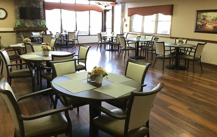 An empty dining area with neatly arranged tables and chairs on a wooden floor.