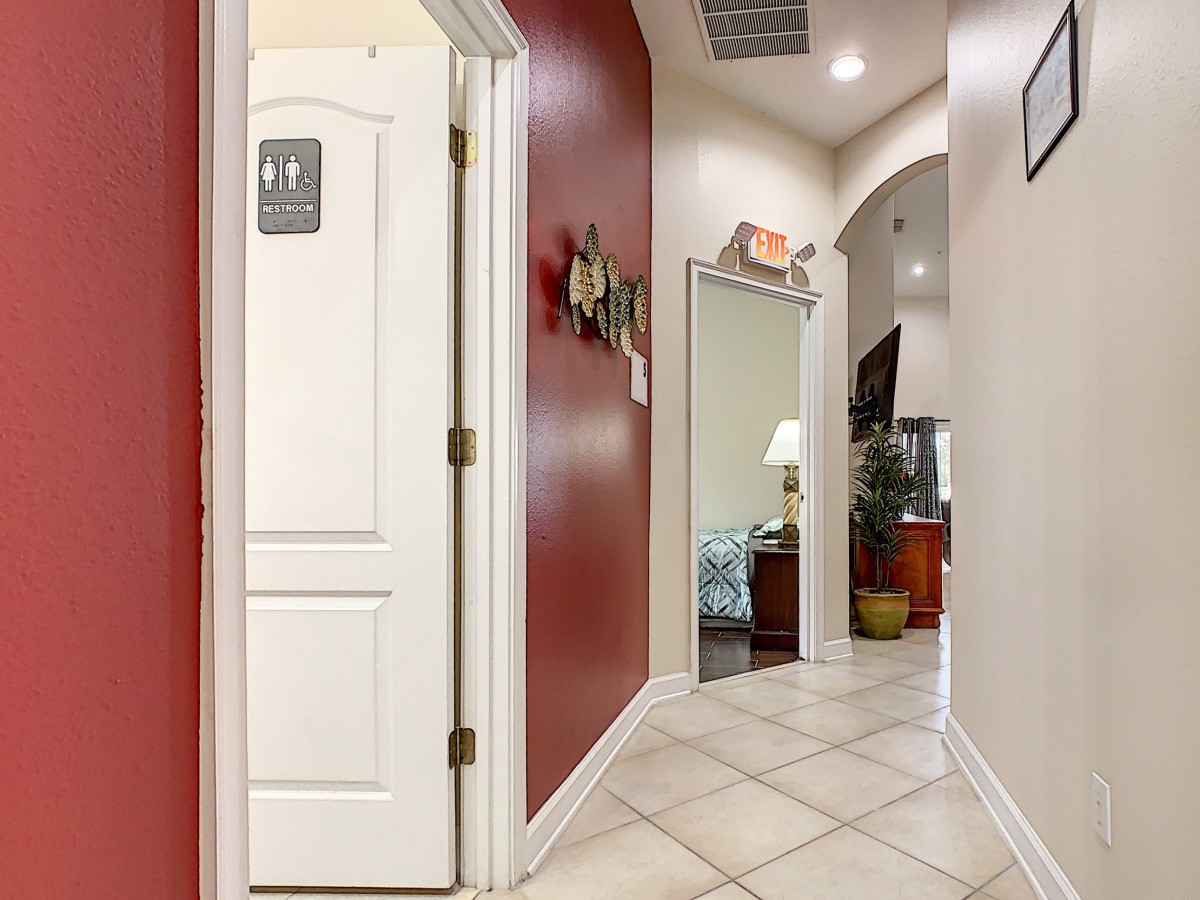 A well-lit hallway with tiled flooring, featuring a red accent wall and office decor.