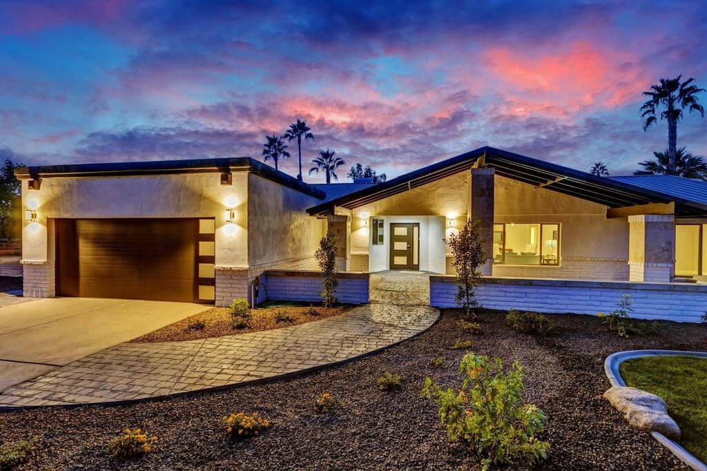 A modern house with a beautifully landscaped driveway at sunset.