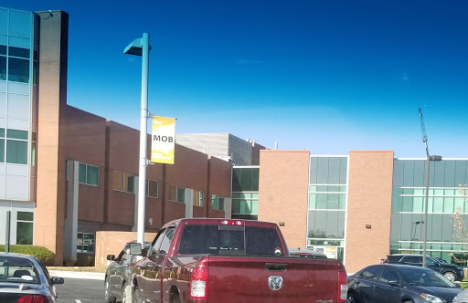 A red truck parked in front of a modern building under a clear blue sky.