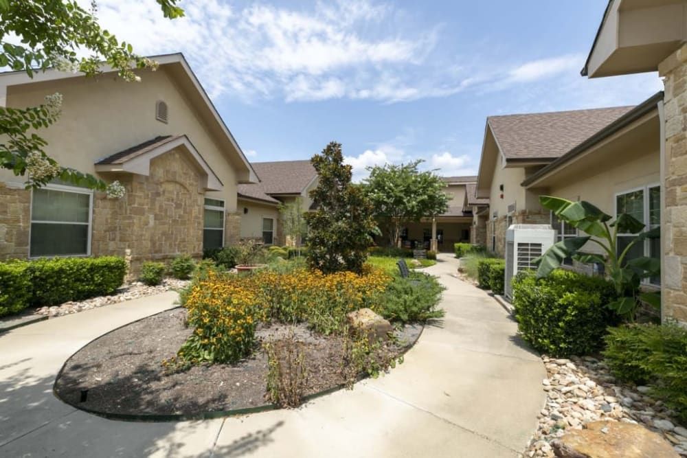 A well-maintained residential area featuring landscaped gardens and a winding pathway between modern houses.
