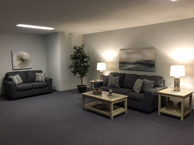 A cozy living room with two sofas, coffee tables, lamps, and an indoor plant.