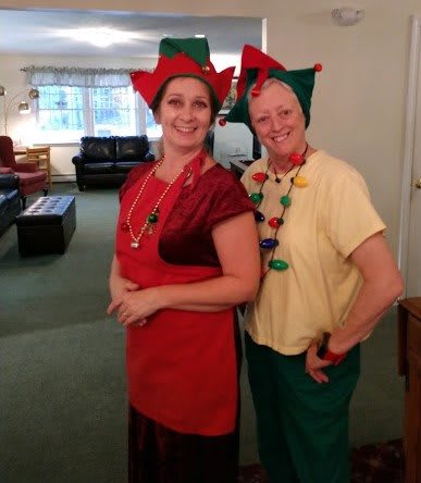 Two people dressed as festive elves in a cozy room.