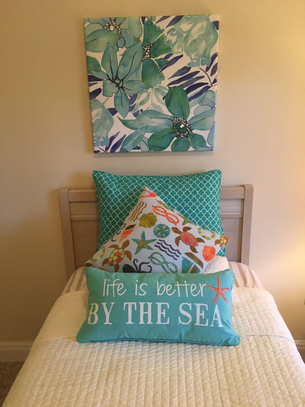 A cozy bedroom setup with coastal-themed pillows and artwork.