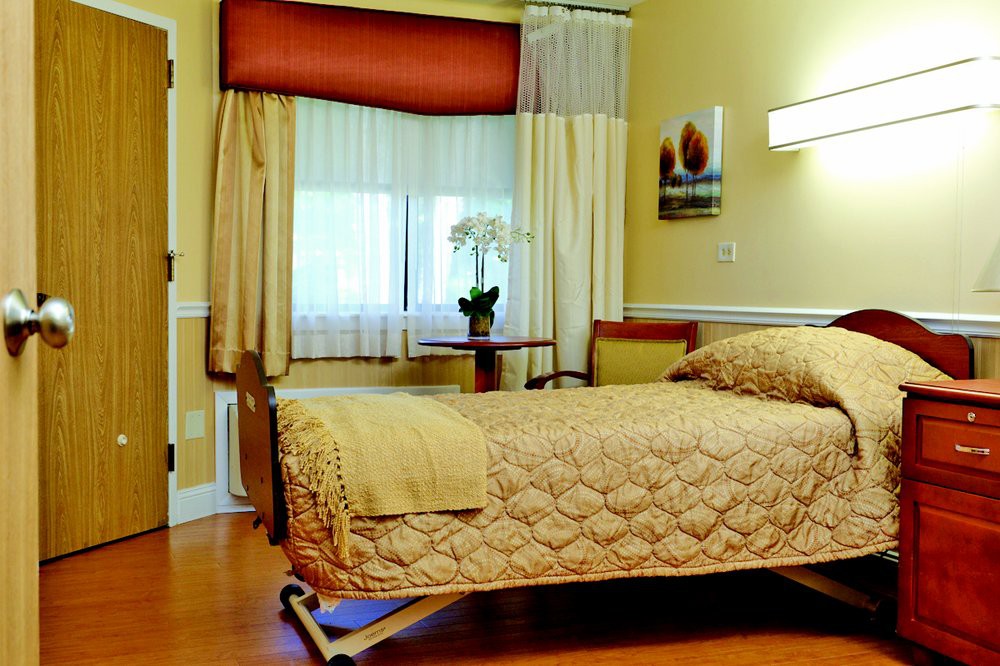 A well-furnished hospital room with a single bed and natural lighting.