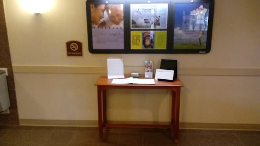 A small wooden table displaying informational materials in a lobby area.