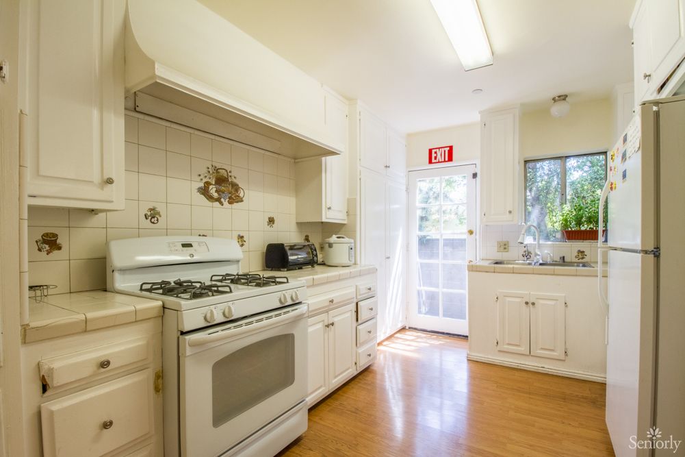 A bright, cozy kitchen with white cabinets and a gas stove.