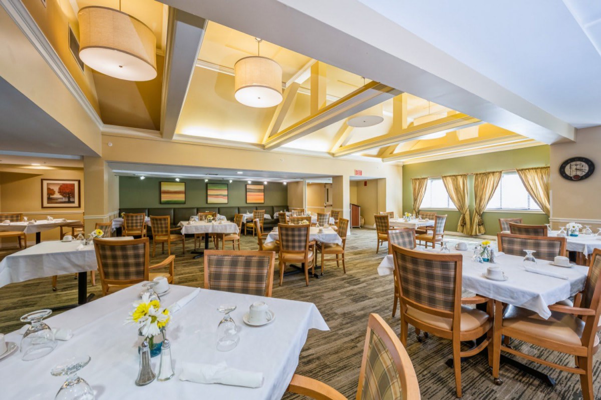 A warmly lit dining room with neatly arranged tables and chairs, featuring elegant decor and soft lighting.