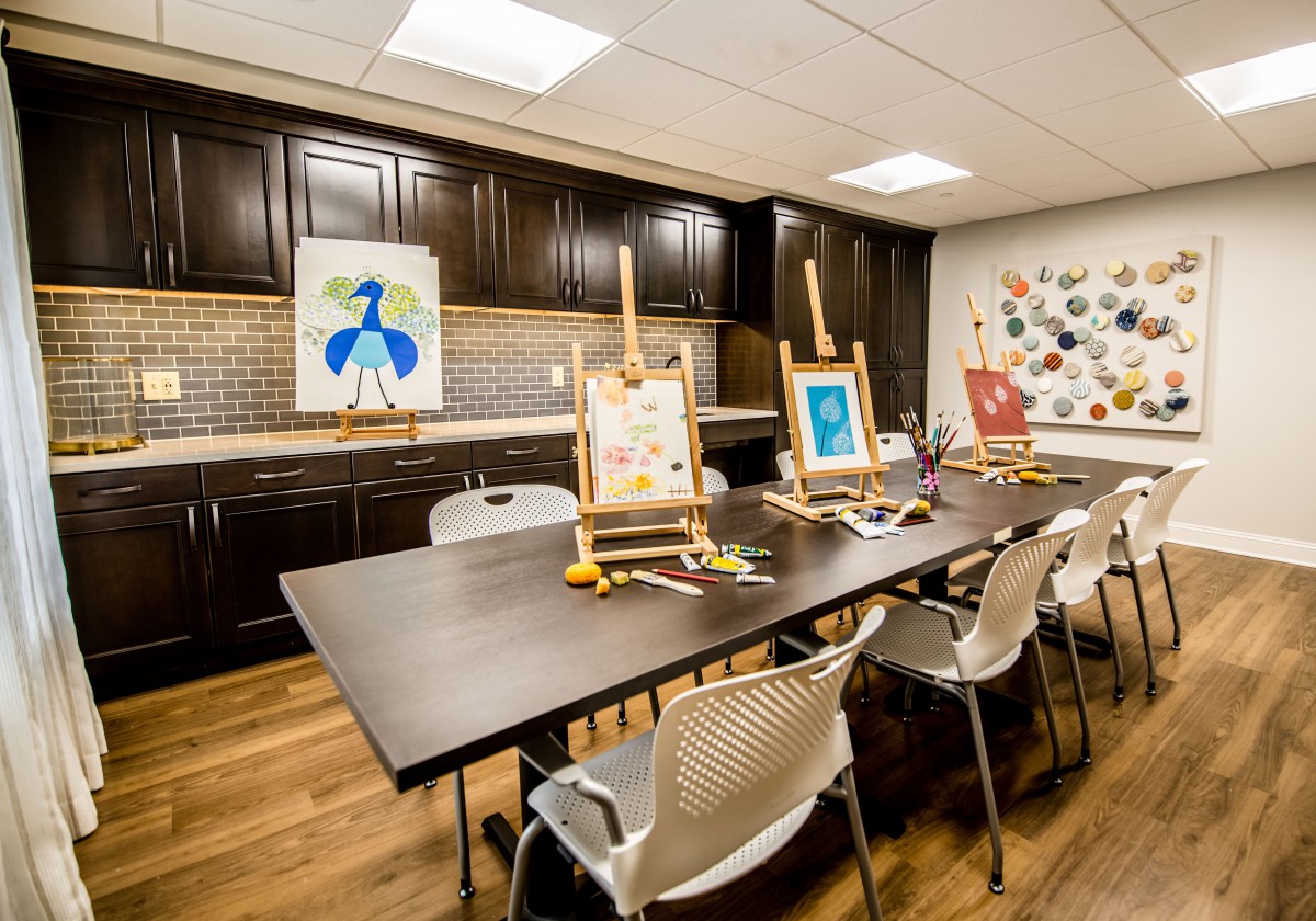 A well-equipped art studio with paintings on easels, surrounded by chairs and set up for a creative session.
