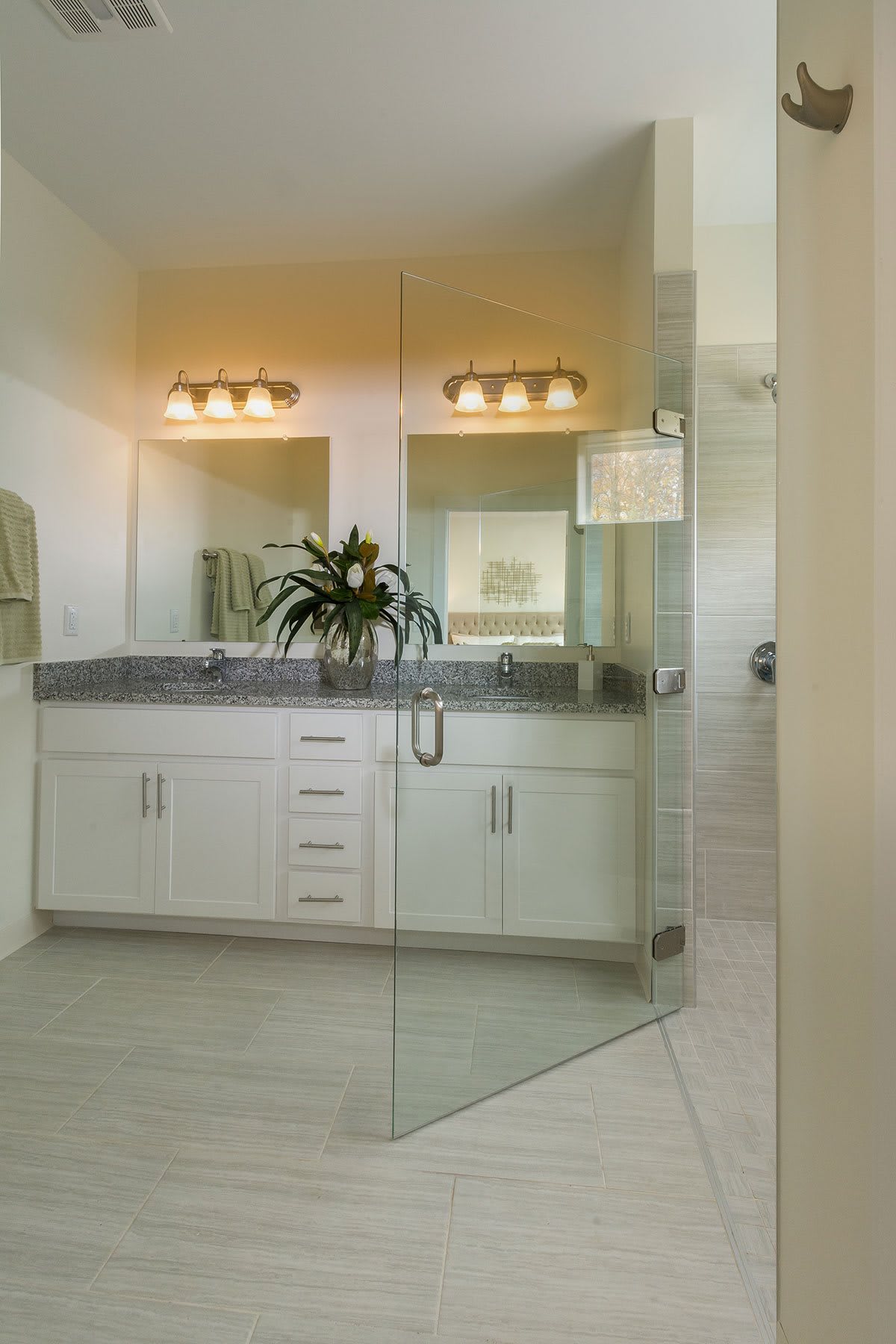 A modern bathroom featuring a glass-enclosed shower, double vanity with mirrors, and stylish lighting.