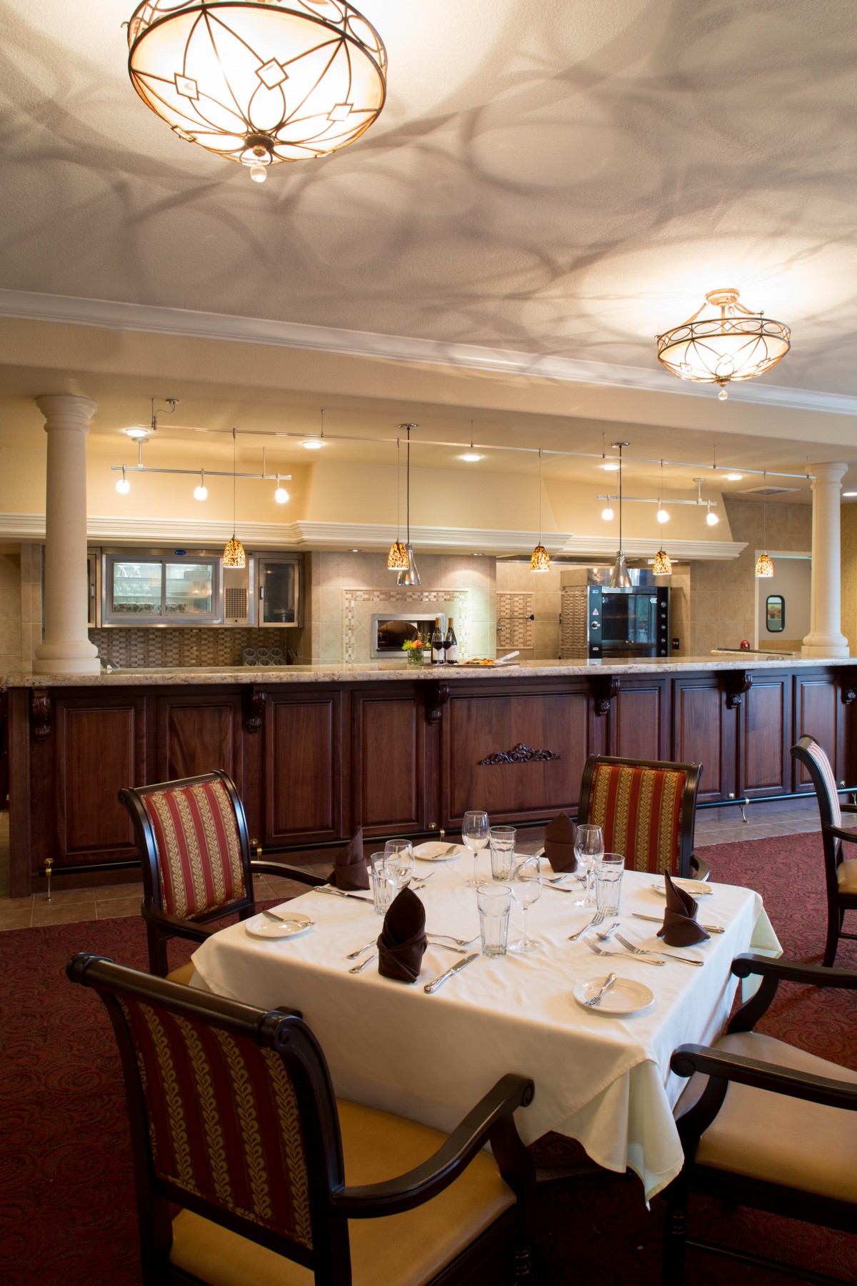 A cozy restaurant interior showcasing a well-set dining table and an open kitchen view.