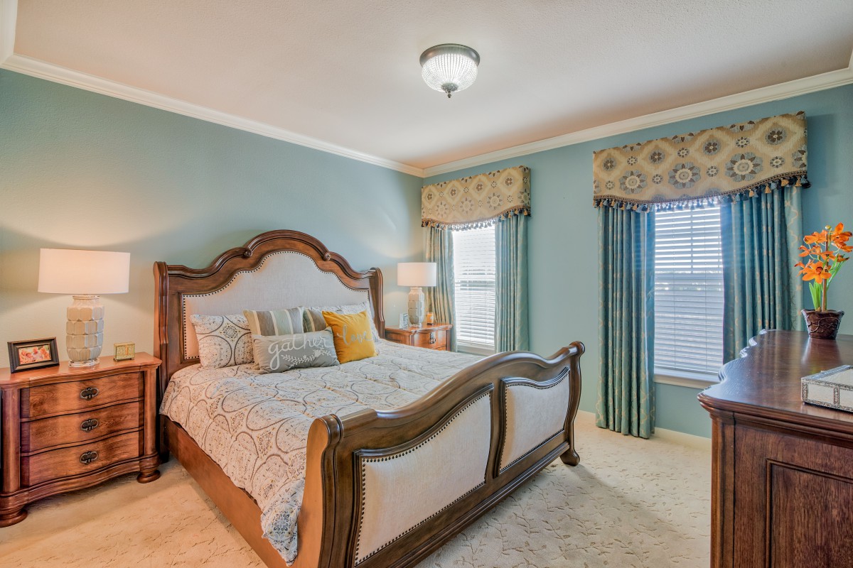 A well-decorated bedroom with a large wooden bed, stylish bedding, and coordinated curtains.