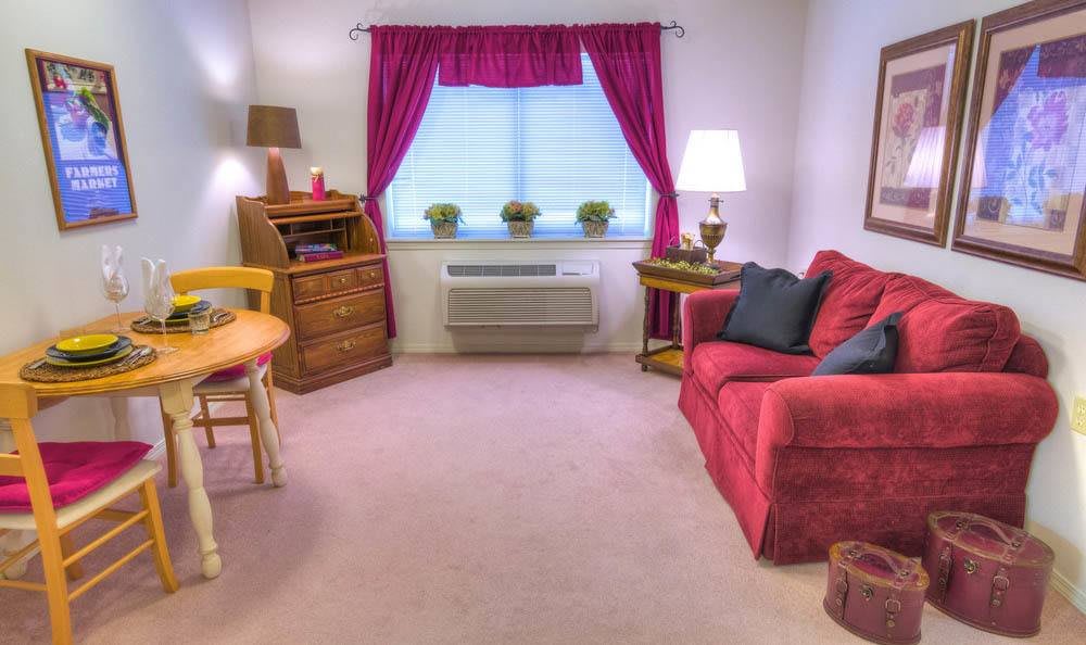 A cozy living room with a red sofa, wooden furniture, and bright pink curtains.