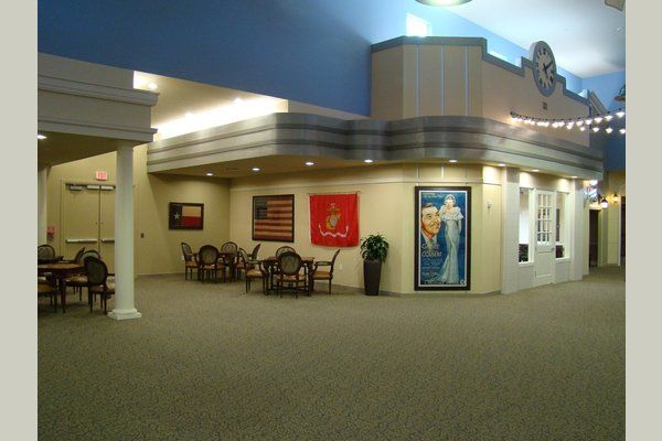 An interior view of a shopping mall with a seating area featuring tables, chairs, and decorative posters on the walls.
