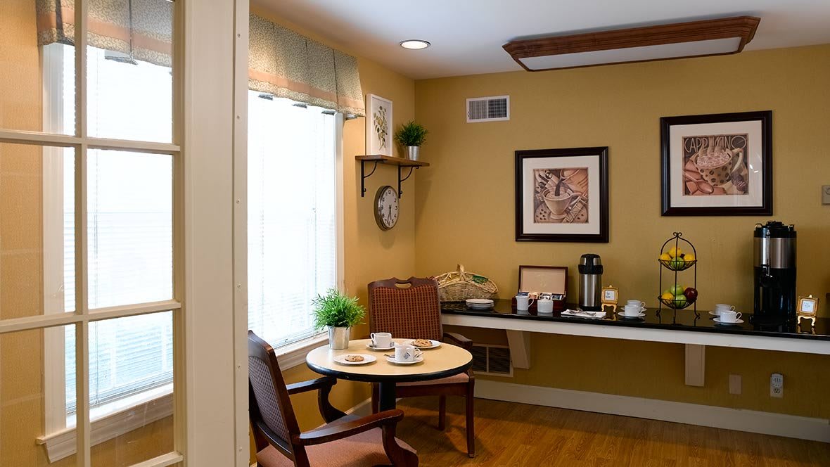 A cozy dining corner with a small table, chairs, and a coffee station by the window.