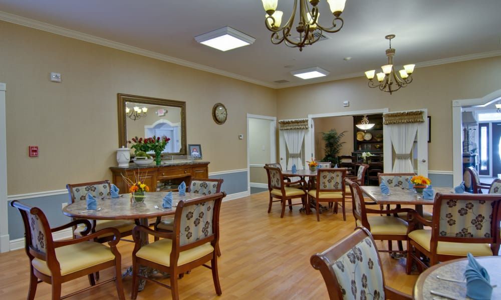 A well-decorated dining room with multiple tables and chairs, featuring chandeliers and elegant decor.