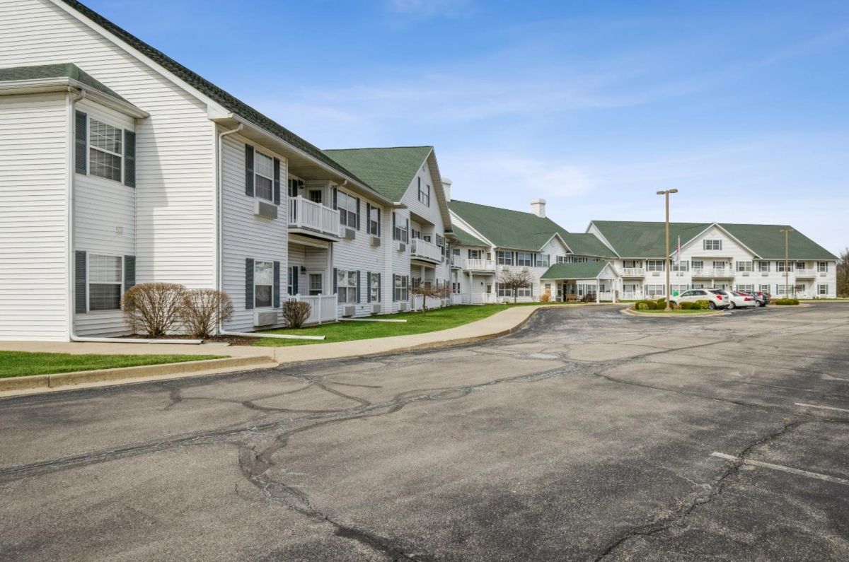 A view of a residential apartment complex with a parking lot in front.