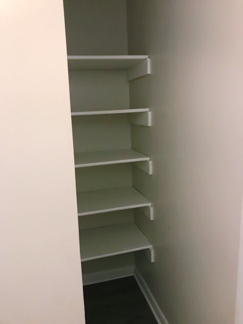 A small closet with multiple white shelves for storage.