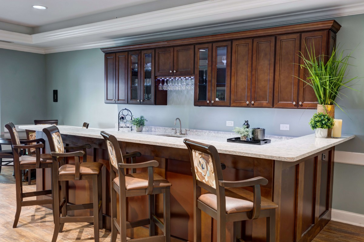 A modern kitchen interior featuring a bar counter with wooden bar stools and elegant cabinets.