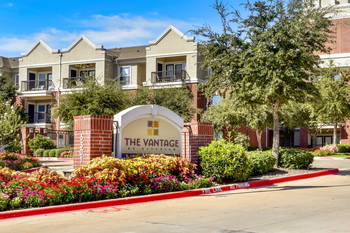 A vibrant apartment complex with well-maintained landscaping and clear signage.