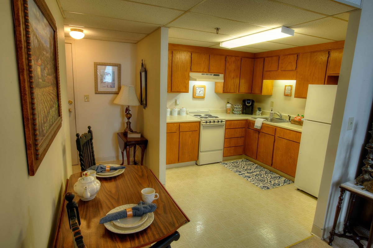 A cozy kitchen and dining area with wooden cabinets and a neatly set table.
