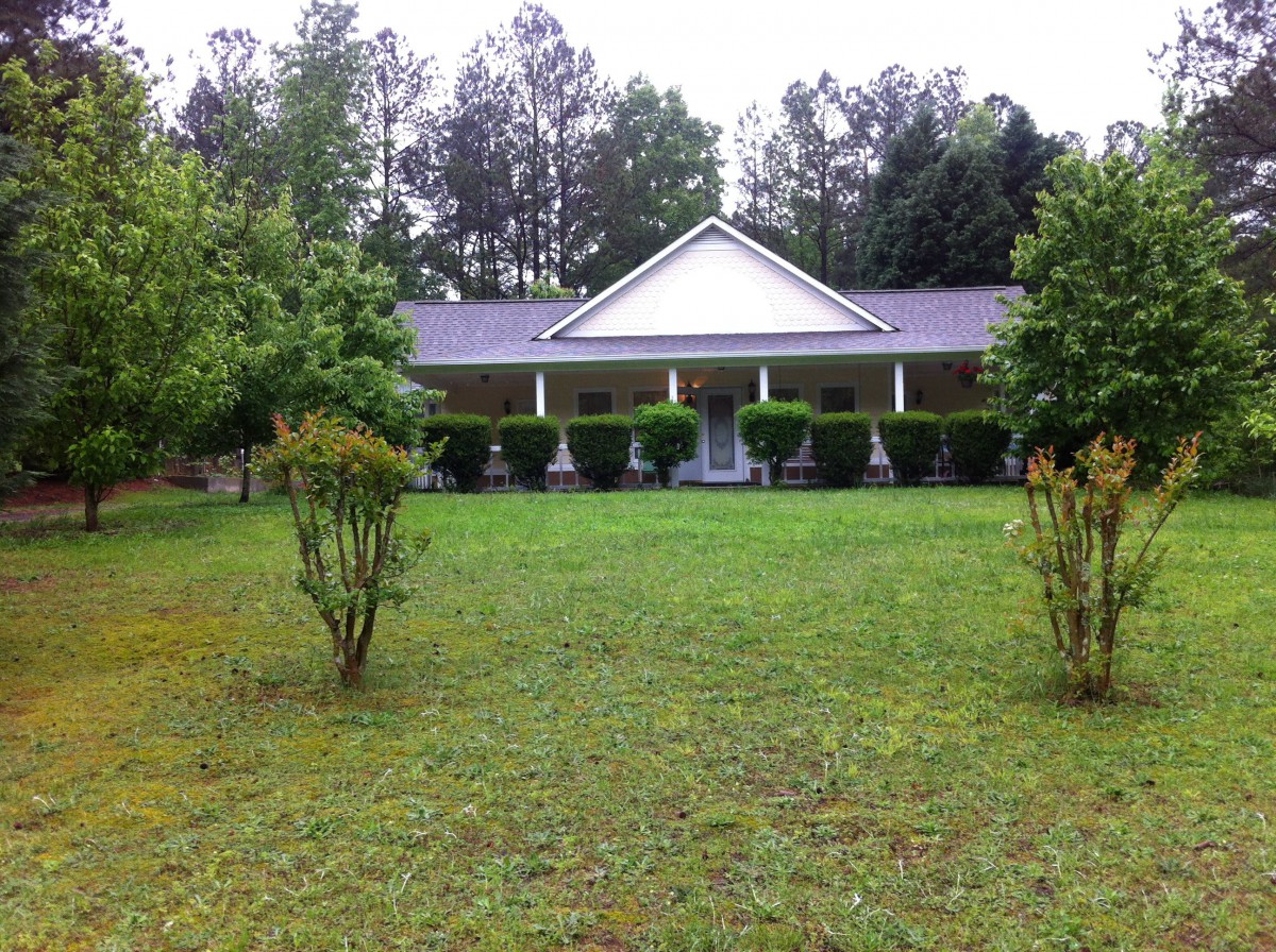 A house with a large front lawn and surrounding trees.