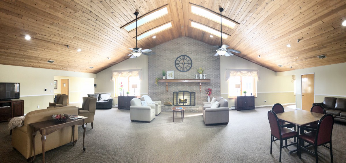 A spacious living room with a vaulted ceiling, skylights, and a cozy fireplace.