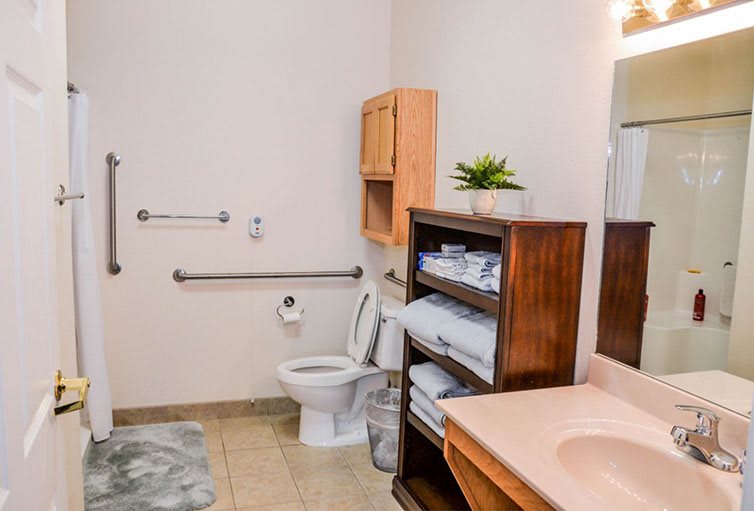 A well-organized bathroom with a toilet, sink, storage shelves stocked with towels, and a small plant for decoration.