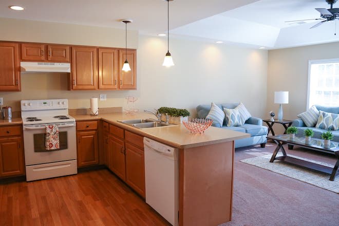 Open concept kitchen and living room with wooden cabinets and pendant lighting.