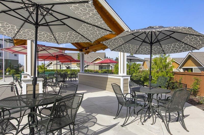 An outdoor patio area with tables, chairs, and umbrellas.