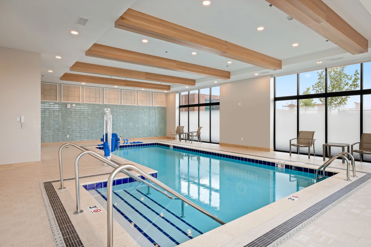 A modern indoor swimming pool with wooden ceiling beams and large windows.