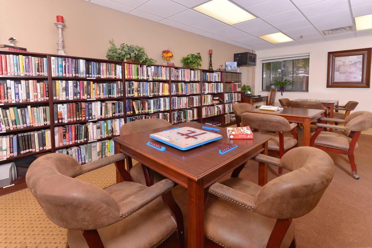 A cozy reading room with bookshelves filled with books and a table surrounded by comfortable chairs.